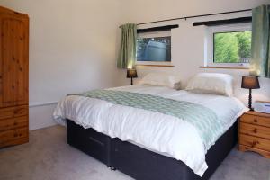 a bedroom with a large bed and two windows at Little Trewin in Helston