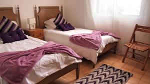 a bedroom with two beds with purple sheets and a chair at OurMadeira - Villa Mary, informal, close to the beach in Porto Santo