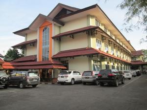 a building with cars parked in a parking lot at Merpati Hotel in Pontianak