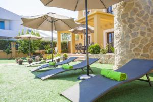 a row of chaise lounges with umbrellas on the grass at Finca Ca Nantonia in Sa Coma