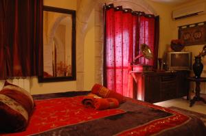 Un dormitorio con una cama con cortinas rojas y una cámara. en Michal's Suites, en Sha'al
