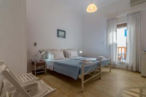 ein weißes Schlafzimmer mit einem Bett und einem Stuhl in der Unterkunft Hotel Delfini in Adamas