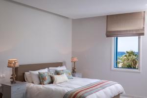a white bedroom with a bed and a window at Poseidon of Paros Hotel & Spa in Chrissi Akti