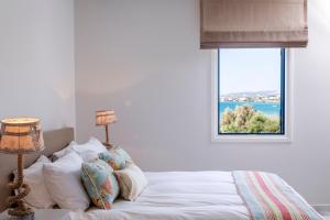 a bedroom with a bed with a window at Poseidon of Paros Hotel & Spa in Chrissi Akti