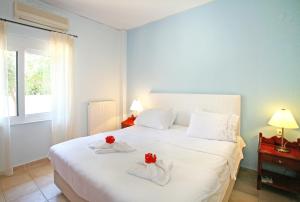カラマキにあるVilla Armonia two bedroom aptのベッドルーム1室(白いベッド1台、赤いバラ2本付)