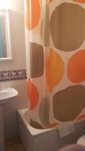 a bathroom with a shower curtain and a sink at Pensión Avenida in Tavernes de Valldigna