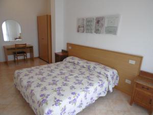 a bedroom with a bed with a floral bedspread at Condominio York in Lido di Jesolo