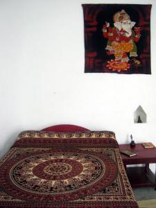 ein Teppich auf einem Bett mit einem Gemälde an der Wand in der Unterkunft Friends in Khajuraho in Khajurāho