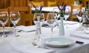 a table with wine glasses and plates and purple flowers at Hotel Farré D'avall in Barruera
