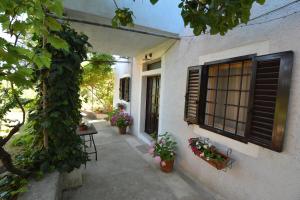 a porch of a house with plants and a window at Apartment Renata in Veli Lošinj