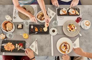 a group of people sitting around a table eating food at Poseidon of Paros Hotel & Spa in Chrissi Akti