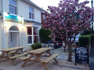a picnic table and a tree in front of a building at Seashells Beach Hotel in Sutton on Sea