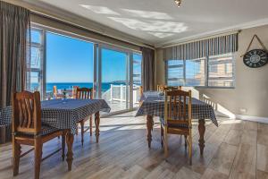 a dining room with a table and chairs with a view of the ocean at Marine Manor in Mossel Bay