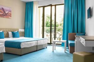 a bedroom with a bed and a window with blue curtains at Arena Mar Hotel and SPA in Golden Sands