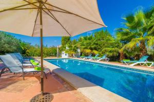 a pool with chairs and an umbrella next to it at Villa Garba in Felanitx