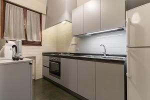 eine Küche mit weißen Schränken, einer Spüle und einem Kühlschrank in der Unterkunft Rialto Bridge Large Venetian Style With Lift in Venedig