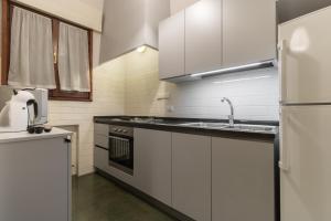 a kitchen with white cabinets and a sink and a refrigerator at Rialto Bridge Big apt with Lift by LionHost in Venice