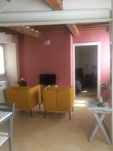 een woonkamer met gele stoelen en een televisie bij Casa Angiola in Cagli