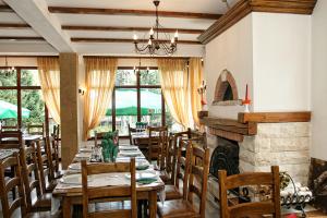 een eetkamer met een lange tafel en een open haard bij Pensiunea Vraja Muntelui in Arieşeni