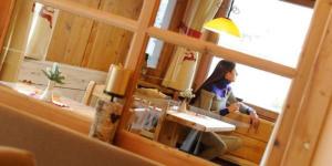 a woman sitting in a room looking out a window at Alpenlife Hotel Someda in Moena