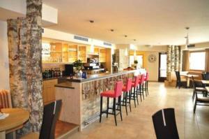 a restaurant with a bar with red bar stools at Alpen Family Hotel Someda in Moena
