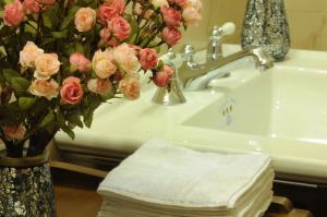 a bathroom with a sink with a vase of pink roses at Hotel Villa Maria in Naples