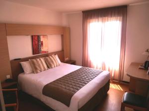 a hotel room with a large bed with a window at Cévenol Hôtel in Millau