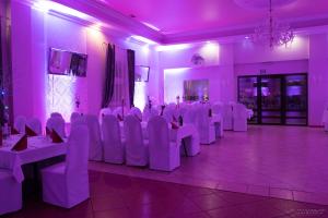 a room with white chairs and tables in a room with purple lighting at Noclegi Europa in Bolesławiec