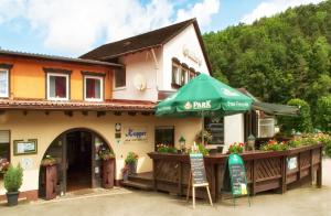 un restaurant avec un parasol vert en face d'un bâtiment dans l'établissement Hotel Kupper, à Eppenbrunn