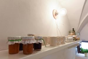 a shelf with several jars and mugs on it at Corte dei melograni-Suite familiare-zona Ostuni in Montalbano