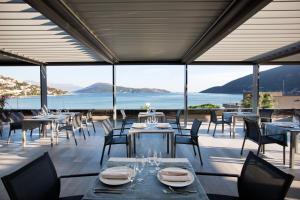 a restaurant with tables and chairs and a view of the ocean at Palmon Bay Hotel & Spa in Herceg-Novi