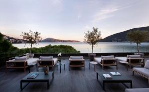 a patio with tables and chairs and a view of a lake at Palmon Bay Hotel & Spa in Herceg-Novi
