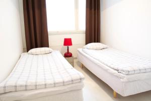 - 2 lits dans une chambre avec une lampe rouge dans l'établissement Torget Apartment Laululinna, à Pori