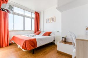 a bedroom with a bed with red curtains and a tv at Residencial Jardim da Amadora in Amadora