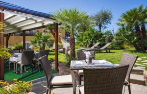 a patio with tables and chairs and palm trees at Hotel Villa Ceselle in Anacapri