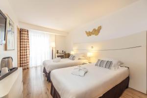 a hotel room with two beds and a television at Hôtel Montaigne & Spa - Cannes Centre in Cannes
