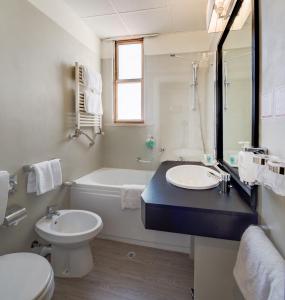 a bathroom with a toilet, sink, and bathtub at Best Western Plus CHC Florence in Florence