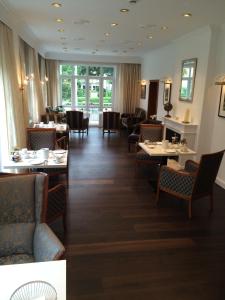 uma sala de jantar com mesas, cadeiras e janelas em Hotel De Insulåner em Langeoog