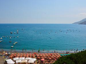 una playa con muchas sombrillas y gente en el agua en Il Miracolo, en Maiori