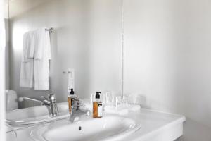 a white bathroom with a sink and a mirror at Hotel Höfn in Höfn