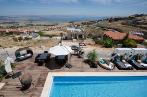 a pool with chairs and umbrellas next to a house at Chateau Glili in Safed