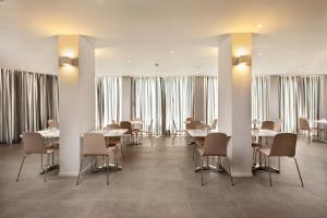 a dining room with tables and chairs and windows at Kriti Hotel in Chania Town