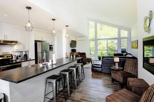 Il comprend une cuisine et un salon avec un bar et un canapé. dans l'établissement Chalet 15 Chemin des Quarante by Les Chalets Alpins, à Stoneham