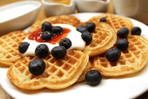 a plate of waffles with blueberries and whipped cream at Stavanger Bed & Breakfast in Stavanger