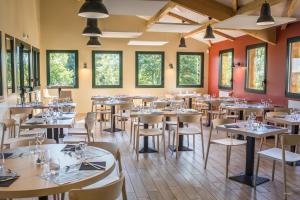 ein Esszimmer mit Tischen, Stühlen und Fenstern in der Unterkunft Archipel Volcans in Saint-Genès-Champanelle