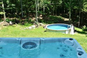 Una bañera en el césped con piscina. en Chalets Alpins -13 Chemin des Skieurs, en Stoneham