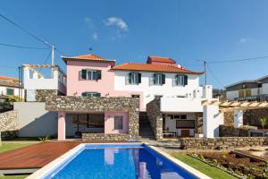 a villa with a swimming pool in front of a house at OurMadeira - Casa das Orquídeas, sunny location in Calheta