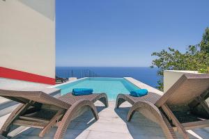 a swimming pool with two chairs and a table and a swimming pool at OurMadeira - Casa do Júlio, Calheta beach view in Calheta