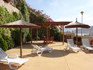 a group of chairs and umbrellas on a patio at Chalet Apartamento Manolo in Faro de Cullera