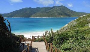 un camino de madera que conduce a una playa con vistas al agua en Refúgio das Dúnas, en Cabo Frío